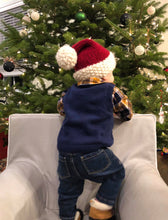 Load image into Gallery viewer, Toddler stand up in chair looking at a Christmas tree and wearing his Santa hat
