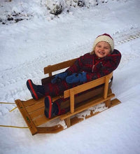 Load image into Gallery viewer, Young child wearing her Santa hat and getting a sled ride in the snow
